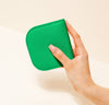 A hand is holding a green wallet.