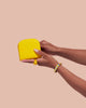 A hand is holding up a yellow vegan leather wallet.