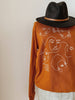 Mannequin wearing an orange crewneck with white line illustrations of women's faces.