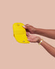 A hand is holding up a light yellow vegan leather wallet.
