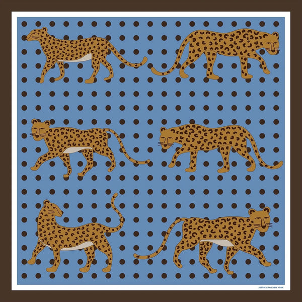 A silk scarf with illustrations of leopards before a blue background with black polka dots.