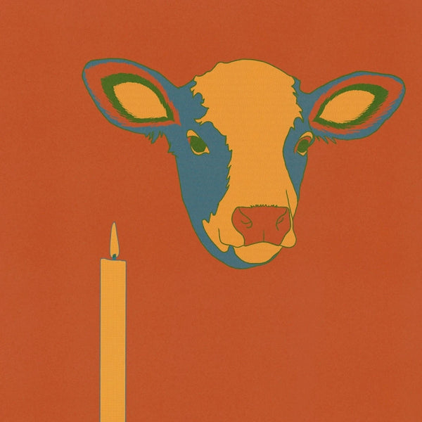 A print of a cow's head next to a burning candle on a bright red background.
