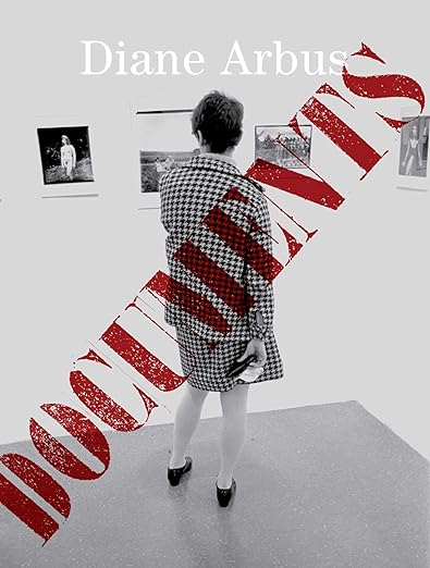 Book cover featuring a black and white photograph of a woman looking at art. The title reads "Diane Arbus: Documents."