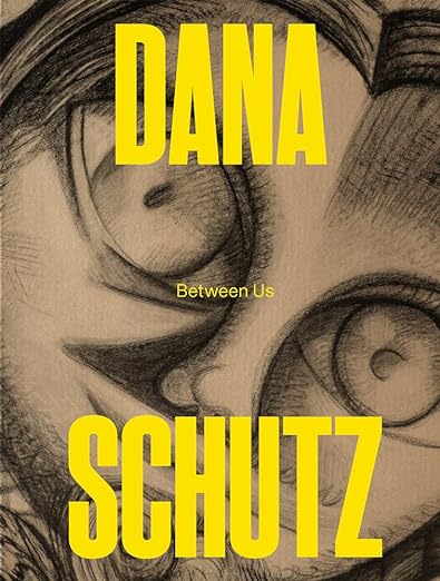 A book cover featuring a black and white drawing of a man's face. The title reads "Dana Schutz: Between Us."