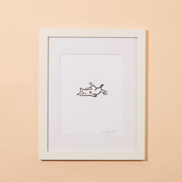 A peachy background with a framed print before it. The print features a small outline of a cat lounging in it. 