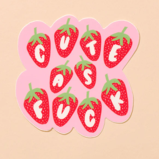 A peach background with a pink sticker in front of it. The sticker is pink with the words "Cute As Fuck" written in individual white letters on mini strawberries. 