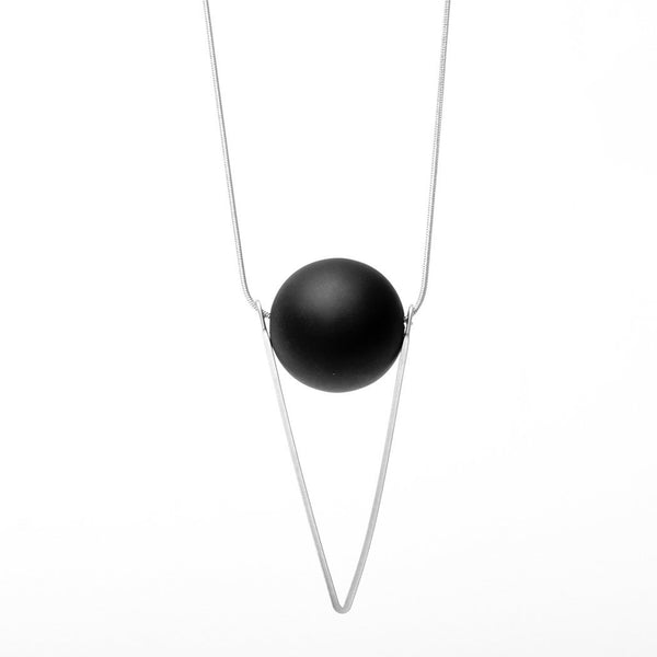 A silver chain with a black orb hanging on it before a white background.