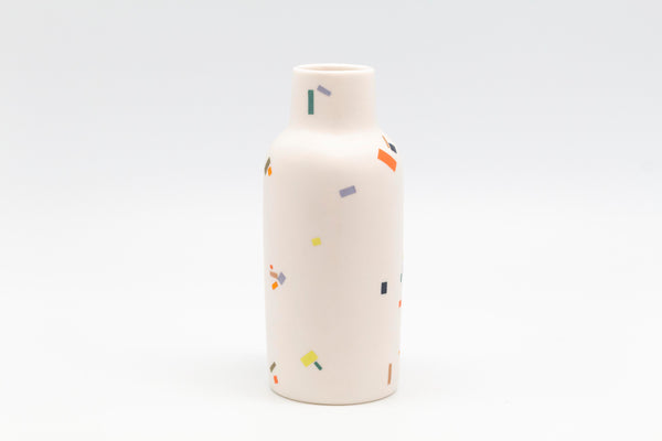 A white ceramic vase with colorful speckles in the shape of tiny rectangles.