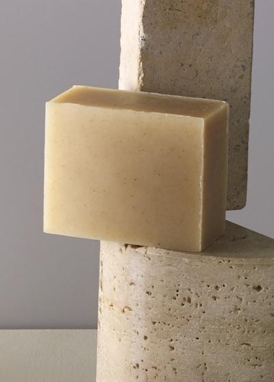 A bar of soap in an oat color standing on a piece of concrete.