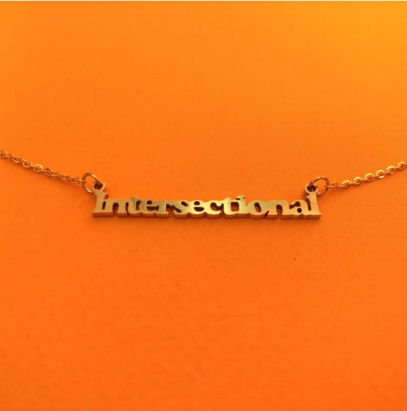 An orange background with a necklace before it. The necklace has the word "intersectional" crafted in gold and attached to each chain. 