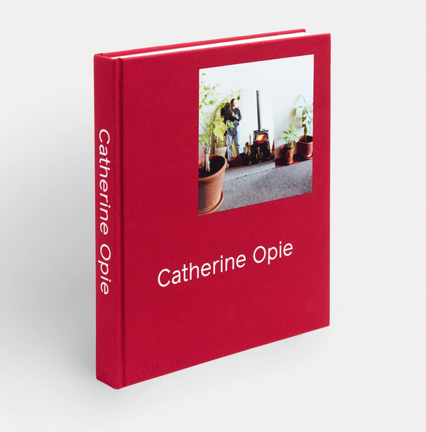 A bright red book cover with a photograph of plant pots and a person in a mirror. The title reads "Catherine Opie."