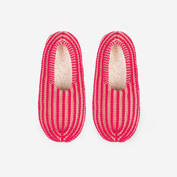 Indoor knit slippers with chunky rib stripes in peach and pink and fully lined with fleece fabric.
