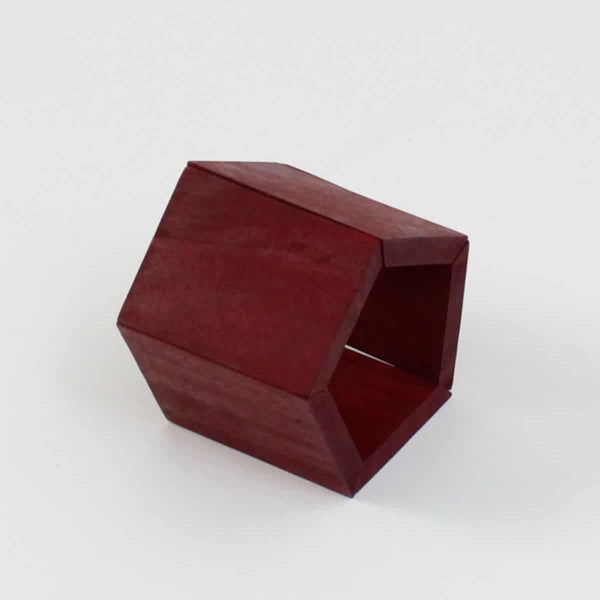 A chunky wooden geometric bracelet in a dark red before a white background. 