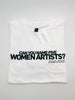 A folded white t-shirt is lying on a black background. On the t-shirt, text in black capital letters reads: "Can you name five women artists?"