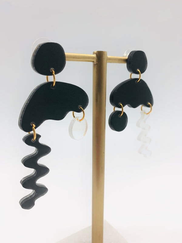 Earrings made of resin in a squiggly shape. They are black with colorful squiggles.