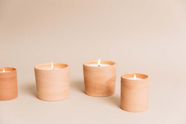 Four candles in red clay cups standing next to each other, burning..
