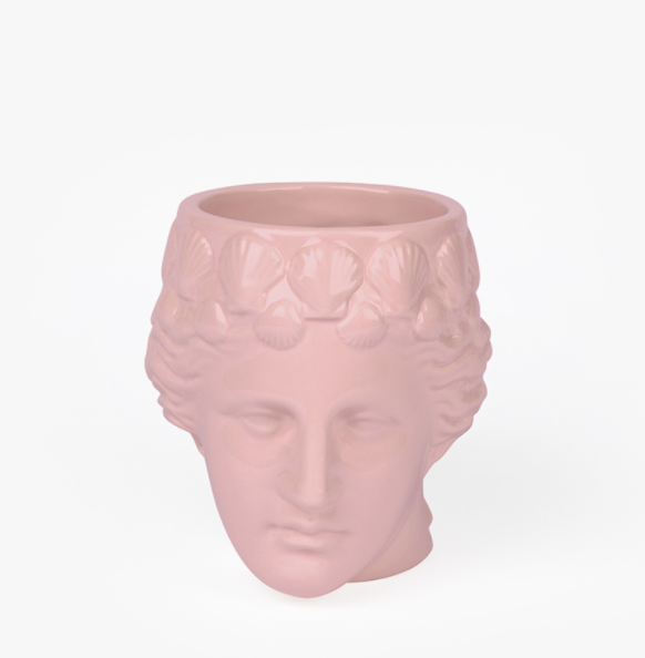 A mug in the shape of a female sculpture's head in pink with shells as her hair.
