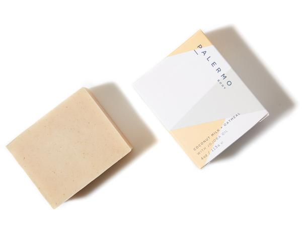 A bar of soap in an oat color next to a paper packaging, reading "Palermo Body."