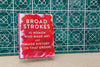 A book is sitting before a tiled wall. The title reads "Broad Strokes: 15 Women Who Made Art and Made History (In That Order)."