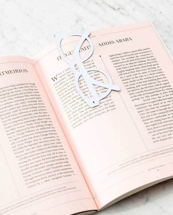 A bookmark in the shape of glasses with a thick white frame, attached to a book.