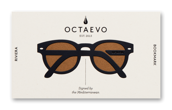 A book mark in the shape of glasses with a thick, black frame, in white packaging with the text "Octaveo" and "Bookmark Riviera Black."