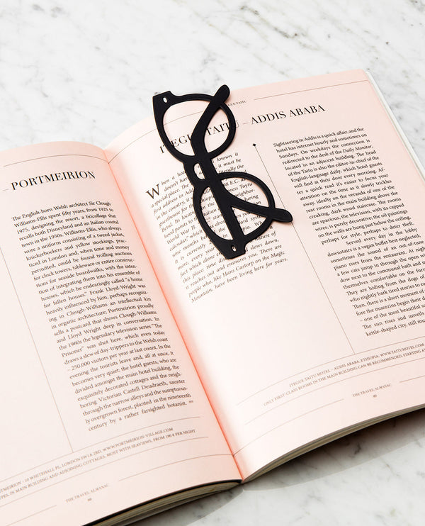 A bookmark in the shape of glasses with a thick black frame, attached to a book.