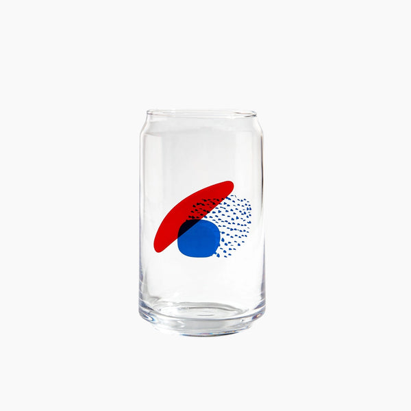 A drinking glass with abstract shapes in red and blue.