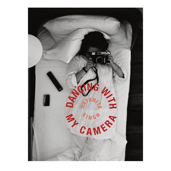 Book cover featuring a black and white photograph of a woman lying in bed taking a photograph from below. The title reads "Dayanita Singh: Dancing with My Camera."