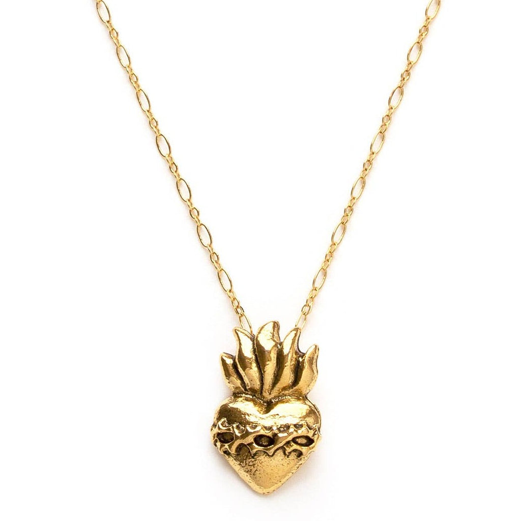 Golden heart charm with a flame on a chain necklace before a white a background.