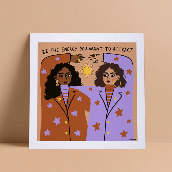 Print with an illustration of two women with dark skin tones and text in black. The text reads "Be the energy you want to attract."