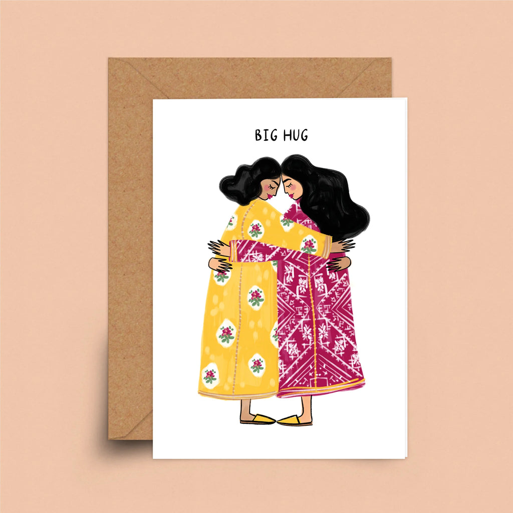 A greeting card depicting two women with dark hair and a medium skin-tone wearing brightly colored dresses. They are embracing under the words "Big Hug."
