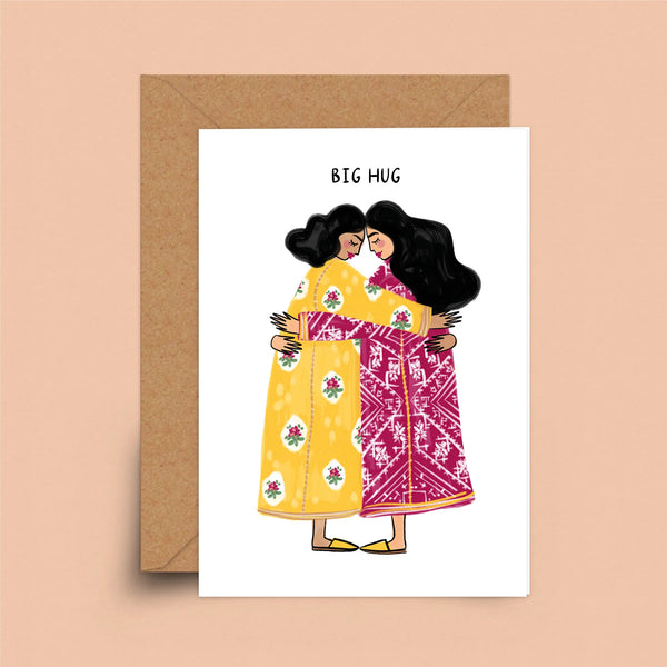 A greeting card depicting two women with dark hair and a medium skin-tone wearing brightly colored dresses. They are embracing under the words "Big Hug."
