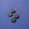 A set of two black, geometric earrings. They are attached to a rose-gold hook.