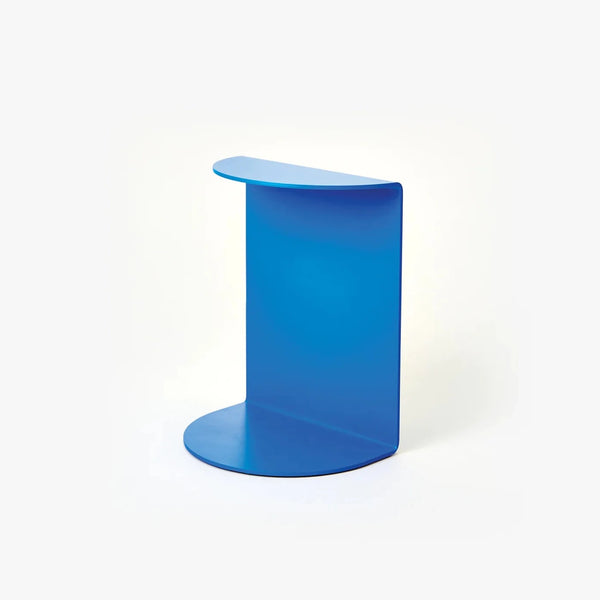 A white background with a bookend before it. The bookend is blue with a curved flap on the top and bottom. 