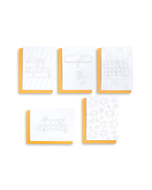 A white background with notecards before it. The notecards are white with a yellow envelope. There are 5 cards with different designs. These designs include a rearview mirror, starbursts, the words "So Far So Good!", the words "100% Stardust" and the words "Living  Legend."