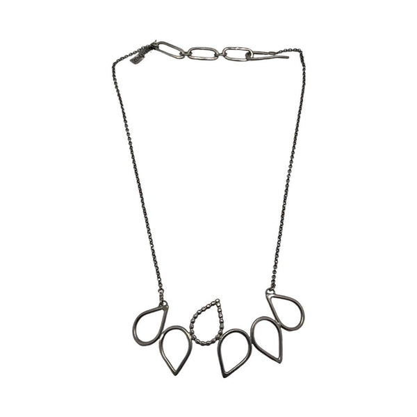 A white background with a necklace before it. The necklace is silver with teardrop-shaped accents hanging from a silver chain. 