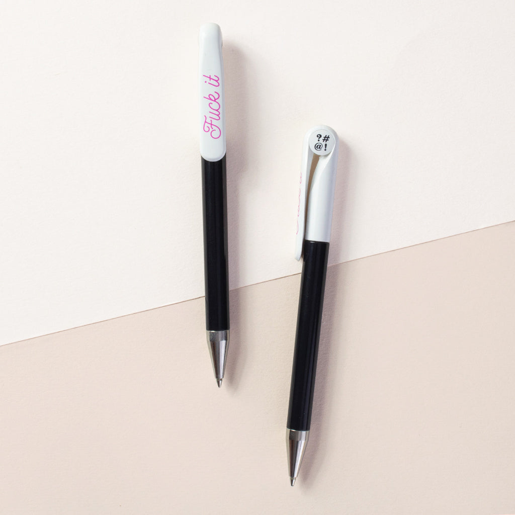 Two pens in black and white next to each other. In pink, the text reads " Fuck it."