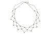 A white background with a silver necklace before it. The necklace is made up of a lattice of silver chains with floral accents. 