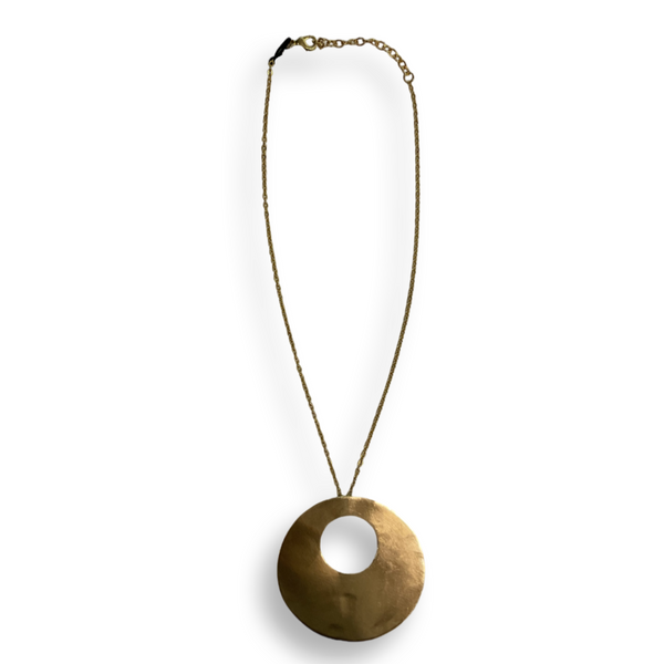 A brass necklace with a circle pendant that has another circle cut out in the middle.
