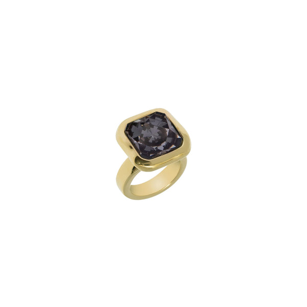 A white background with a golden ring in front of it. The ring has a square shaped setting and features a black crystal 
