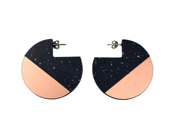 A pair of earrings in black and rose gold in a round shape with a silver stud.