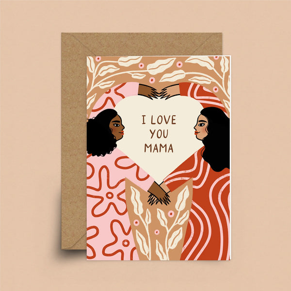 A greeting card with a brown envelope. A mother and daughter with patterned dresses are making a heart with their arms. Inside of the heart are the words "I Love You Mama." The background is beige with white leaves. 