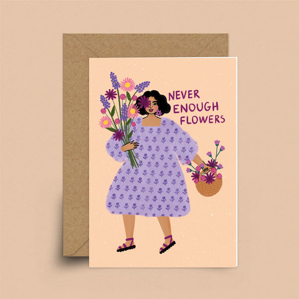 A coral card with a brown envelope. A woman with short, dark hair and a medium skin-tone is on the card. In one hand she is holding a bouquet and in the other she is holding a basket of flowers. Behind her are the words "Never Enough Flowers."