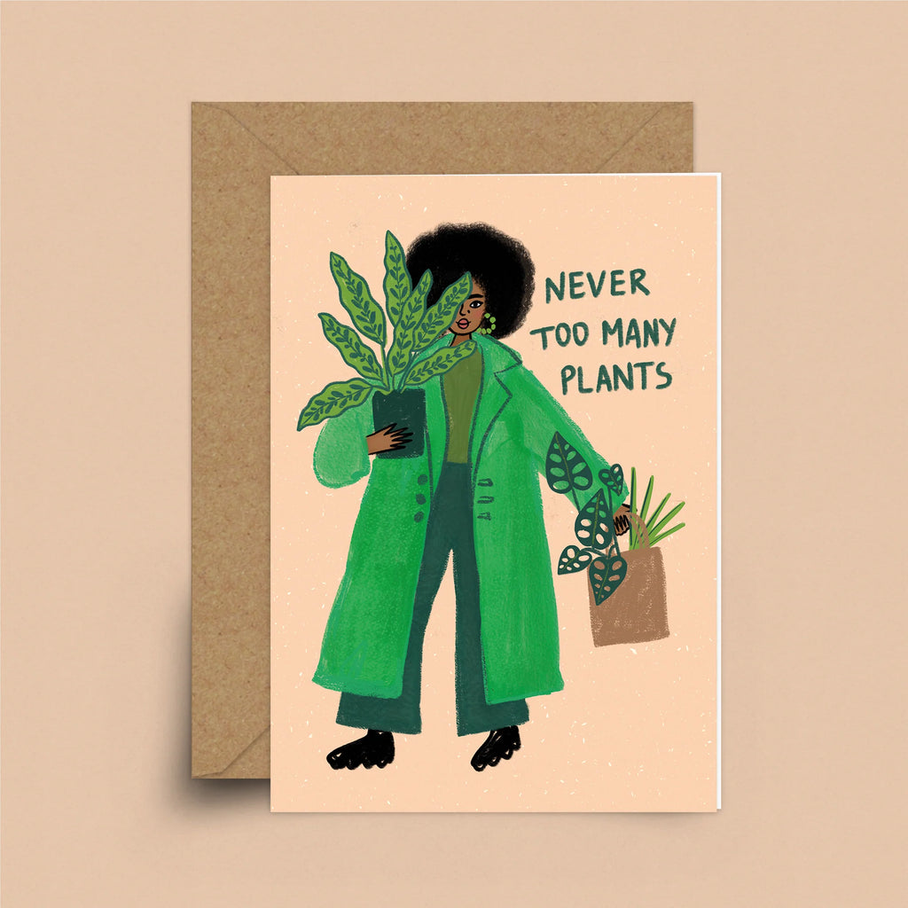 A coral greeting card with a brown envelope. A black woman with natural hair in a green trench coat is holding a potted plant. In her other hand is a basket of plants. Behind her are the words "Never Too Many Plants"