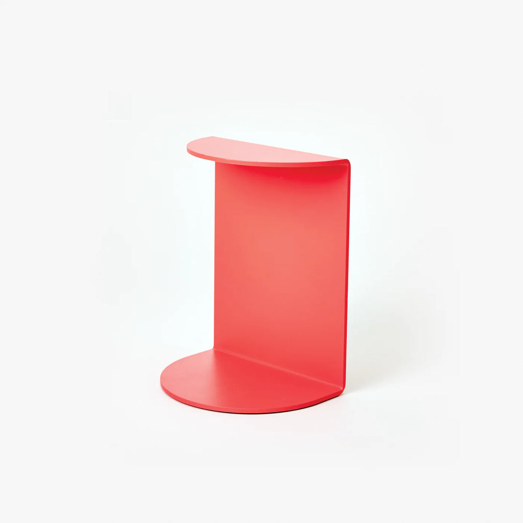A white background with a bookend before it. The bookend is red with a curved flap on the top and bottom.