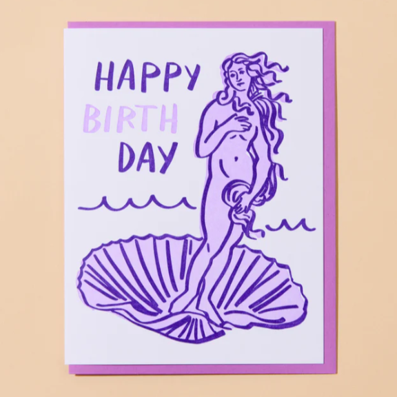 A peachy background with a white card in front of it. The card features the goddess Venus with the words "Happy Birthday" written in purple letters. 