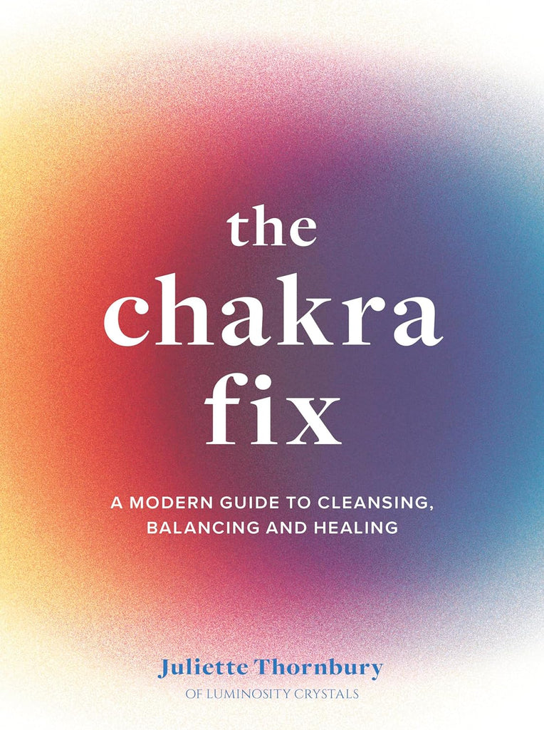 A white book with a rainbow gradient in the middle. The title "The Chakra Fix" is in large, white letters in the foreground. Below the title are the words "A Modern Guide to Cleansing, Balancing and Healing."