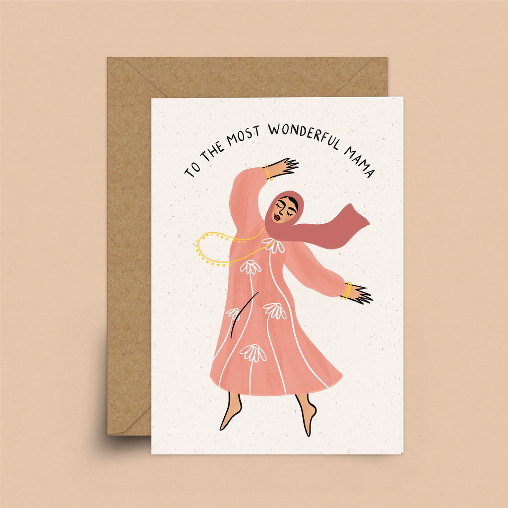 A white greeting card featuring a woman dancing barefoot. The woman is wearing a blush-colored hijab. She is also wearing coral, long-sleeved dress with white daisies in a pattern around it. Her golden necklace is swaying as she dances. Above her are the words "To The Most Wonderful Mama."