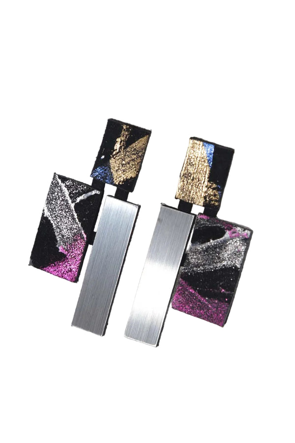 Pair of earrings with geometric design on a white fabric background