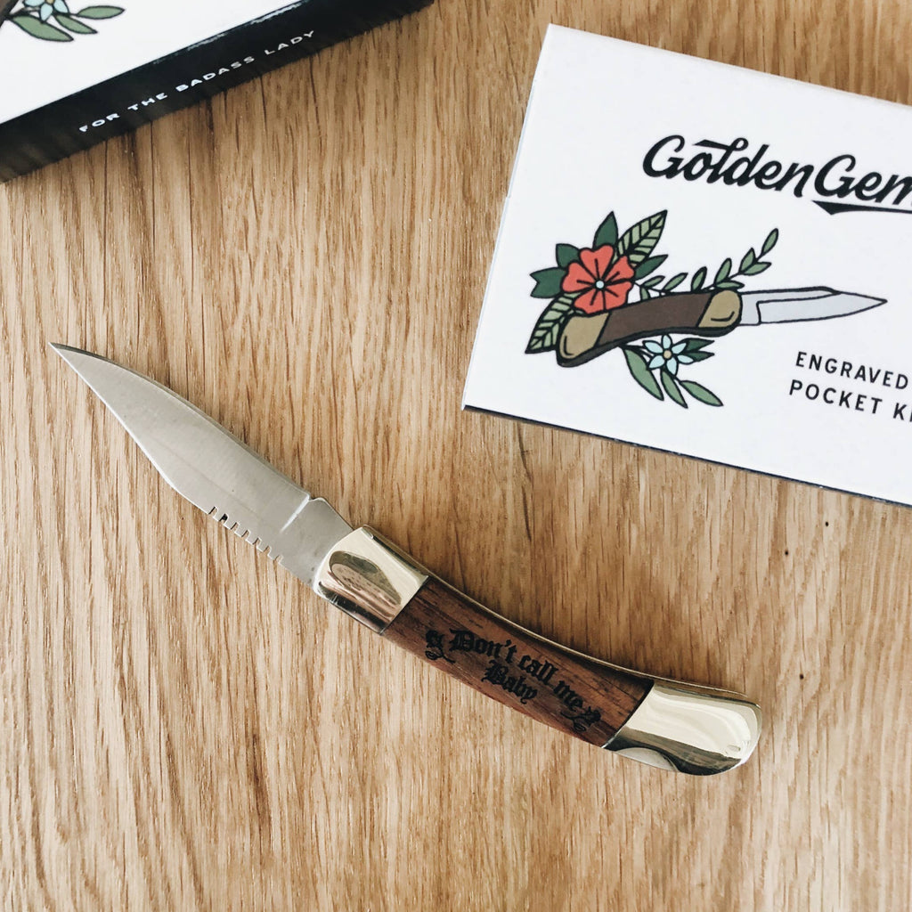 A wooden pocket knife with the text "Don't call me baby" embossed onto it.